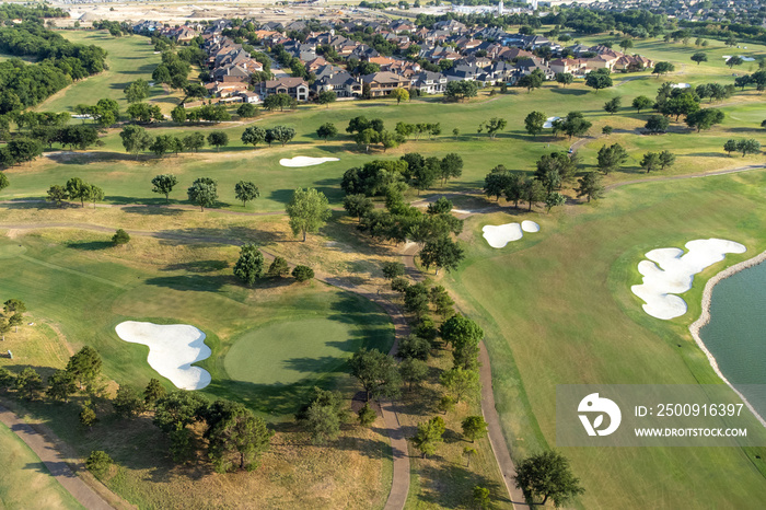 Aerial overview of luxury villas located around green zone and golf playground in the summertime.