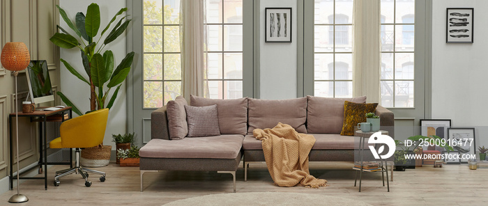 Grey sofa and working table computer style in the living room in front of the window, pillow carpet 