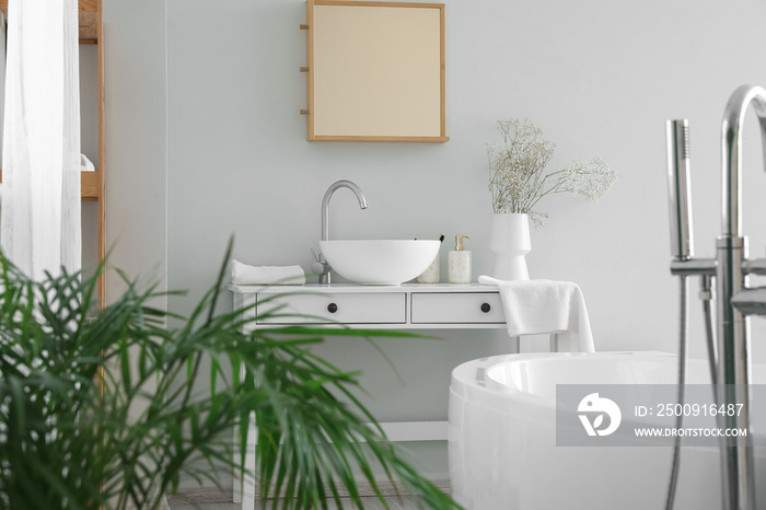 Table with sink and flowers in interior of light bathroom