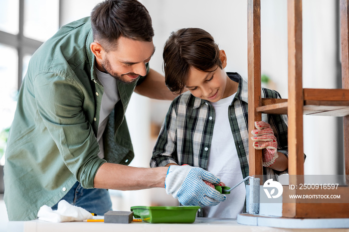 renovation, diy and home improvement concept - father and son in gloves with paint roller painting o