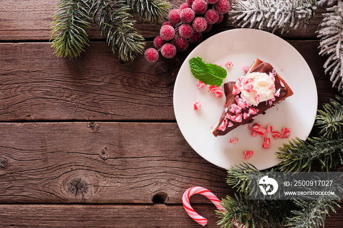 Christmas candy cane chocolate cheesecake. Top view corner border over a dark wood background with c