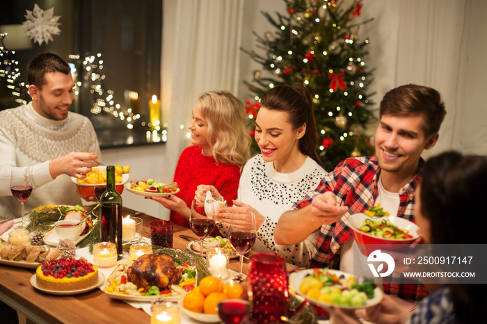 holidays and celebration concept - happy friends having christmas dinner at home and eating food