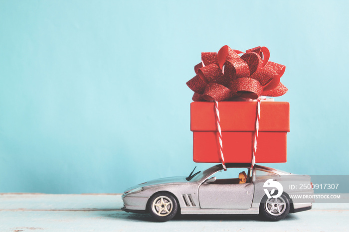 Red gift box on car toy with blue pastel color background, retro filter effect