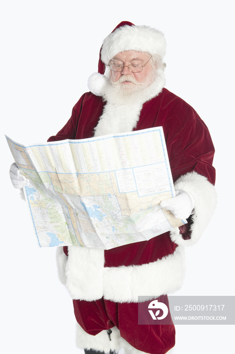 Man dressed in Santa Claus reading road map isolated over white background