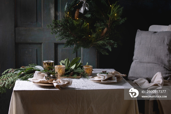 Christmas or New year table setting with empty ceramic plates, napkins, Christmas thuja wreath, lumi