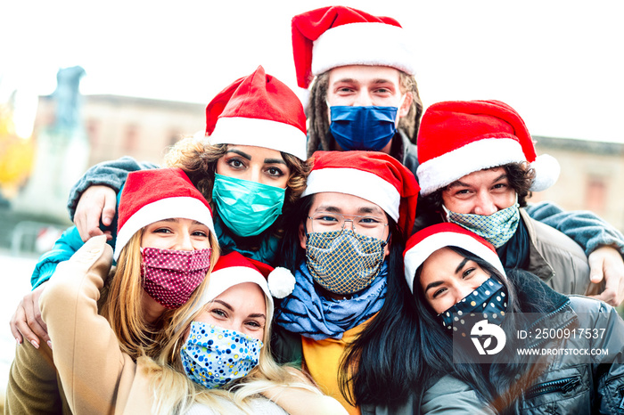 Multiracial friends taking selfie wearing face mask and santa hat - New normal Christmas holiday con