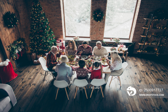 Above top high angle view of noel evening family gathering in loft living room. Grey-haired grandpar