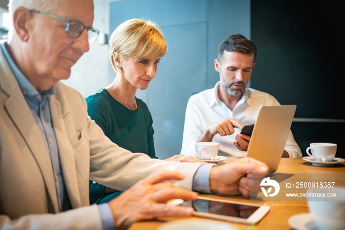 Group of business people using electronic devices in cafe