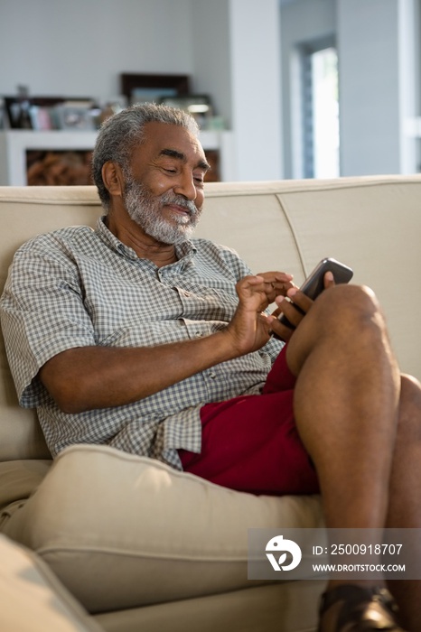 Senior man using mobile phone in the living room