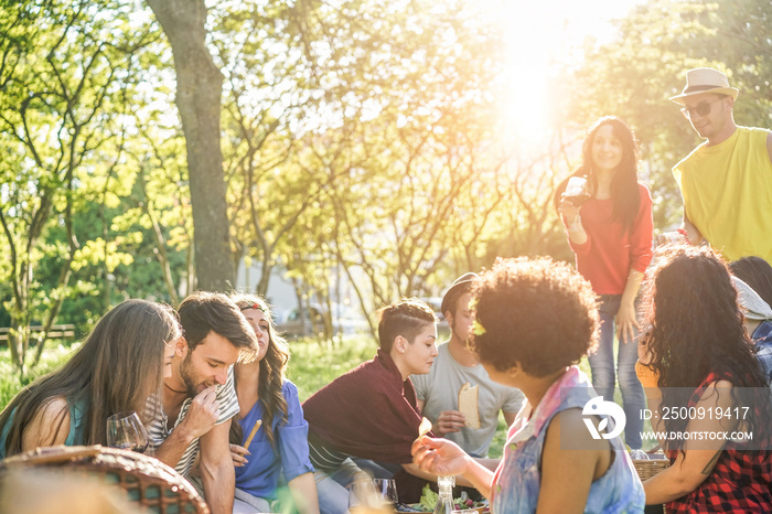 Happy friends eating and drinking red wine at picnic party outdoor