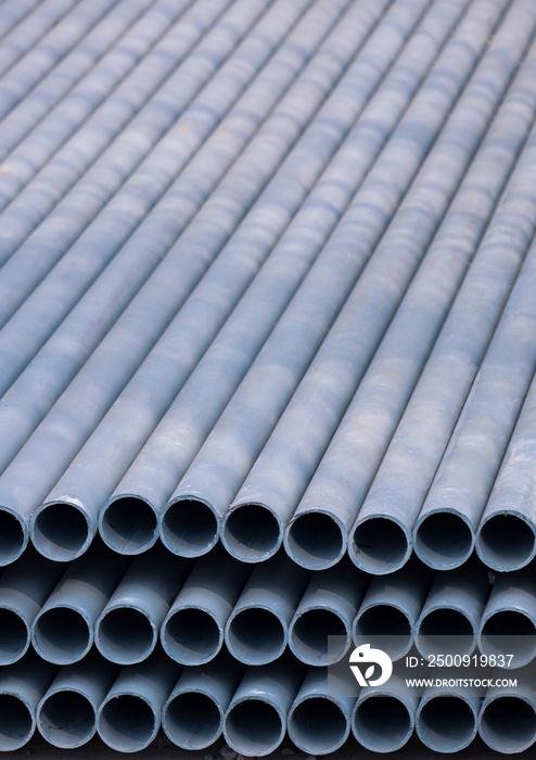 Stack of gray galvanized pipes material inside of construction site in vertical frame
