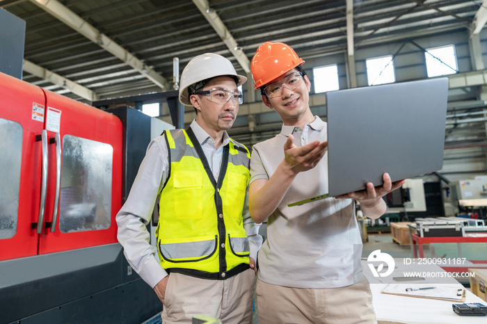 两个工程师穿保护工作服戴着安全帽在工厂工作