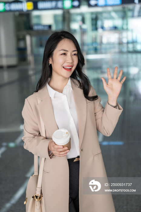 商务女士在机场拿一杯咖啡招手
