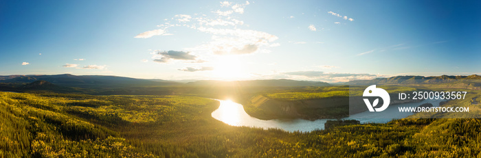 Beautiful View of Scenic Valley from Above alongside Winding River, Forest and Mountains at Sunset. Aerial Drone Shot. Taken near Klondike Highway, Yukon, Canada.