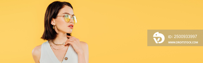 panoramic shot of elegant woman in sunglasses posing isolated on yellow