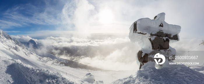 Whistler, British Columbia, Canada. Beautiful Panoramic View of Statue on top of Blackcomb Mountain with the Canadian Snow Covered Landscape in background during a cloudy and vibrant winter sunset.