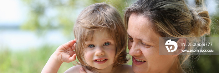 Happy little smiling child in the arms of the mother on a natural background