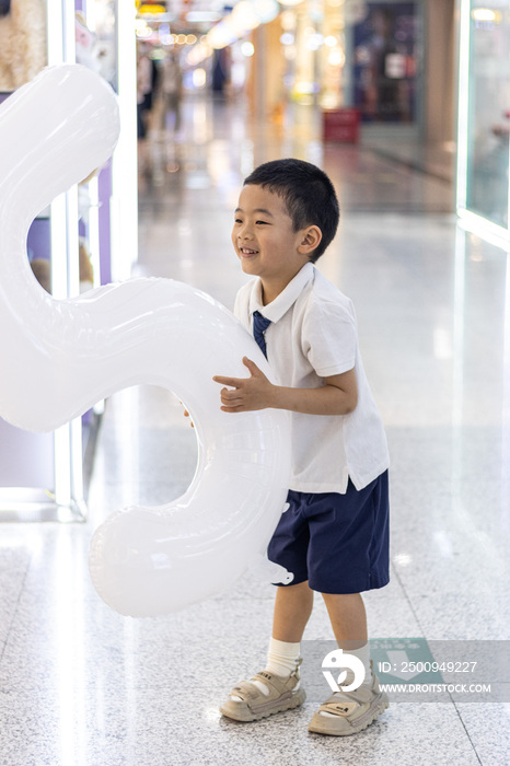 一个抱着充气字母气球的小男孩