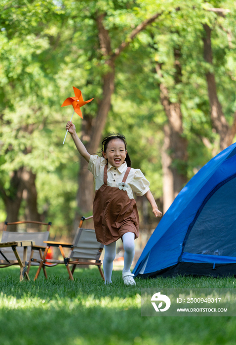 小女孩在草地上举着风车开心奔跑
