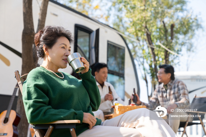 一个老年女人坐在房车露营地喝咖啡
