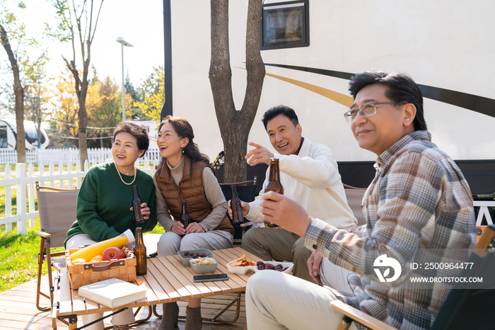 一群中老年人坐在房车露营地喝啤酒聊天