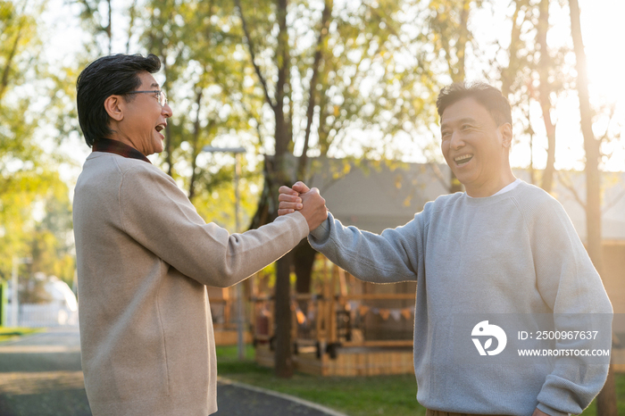 两个中老年男人开心地握手