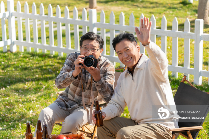 两个老年男人坐在露营地看数码相机