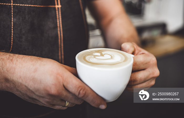 Latte art, professional barista presenting cup of coffee