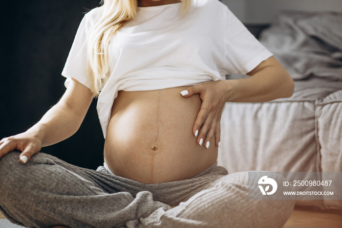 Pregnant belly close up photo how woman practicing yoga