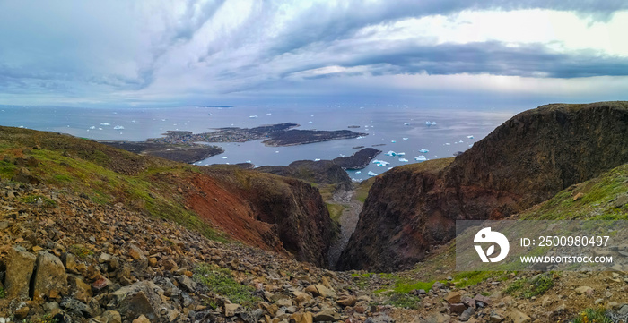 Blue ocean bay with a green and rocky coastline and beautiful mountains, Qeqertarsuaq, Greenland