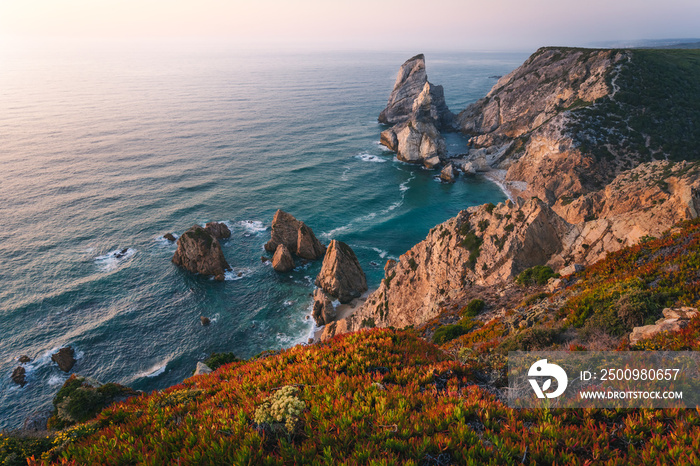 Praia da Ursa. Sintra Region. Portugal. Ursa Beach scenic seascape with sea stacks and cliffs in evening sunset light on Atlantic Ocean coast