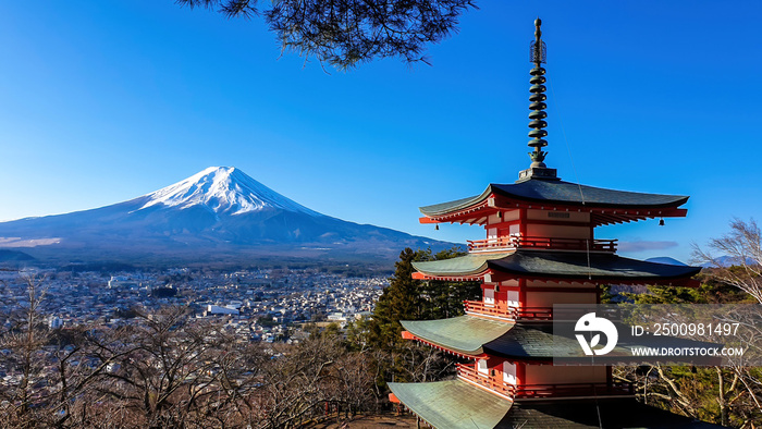 View on Chureito Pagoda and mountain of the mountains Mt Fuji, Japan, captured on a clear, sunny day in winter. Top of the volcano covered with snow. Trees aren’t blossoming yet. Postcard from Japan.