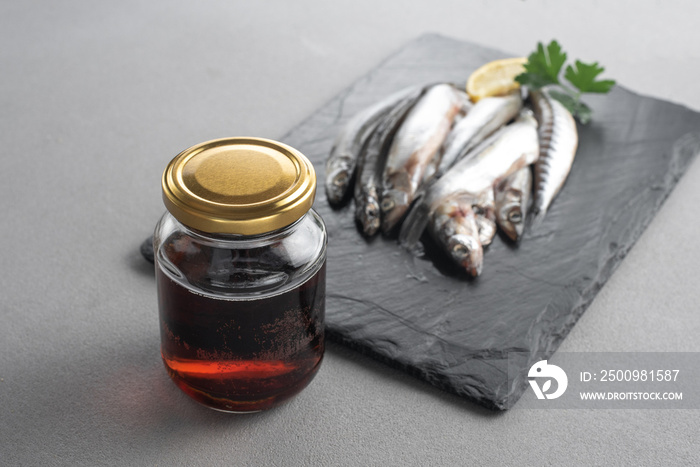 Garum is a fermented fish sauce. Prepared by fermentation from fish, salted garum sauce in a bottle on a gray background. Garum fish sauce made from anchovies on the grey background