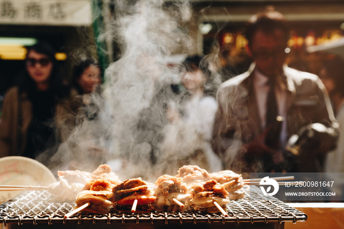 grilled seafood scallop and sea ​​urchin eggs skewer with smoke, japanese street food at Tsukiji Fish Market, Japan. selective focus and film style.