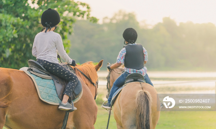 Kids learn to ride a horse near the river before sunset.