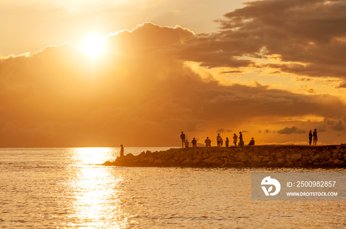 Tourists and fishermen watching amazing sunset from the pier of Mandre village on Pag island, Croatia