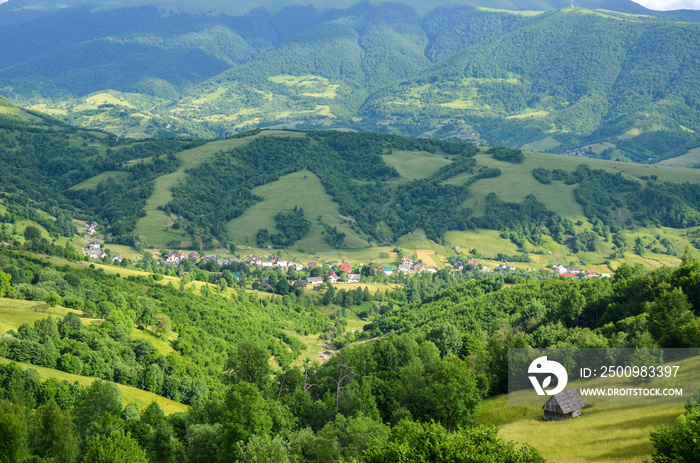 Colorful landscape with green meadows and small village in Carpathian Mountains. Top view of mountain countryside. Kolochava, Transcarpathian, Ukraine