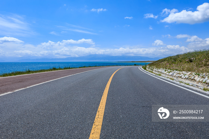 Asphalt road and lake with sky clouds natural scenery in Xinjiang, China.