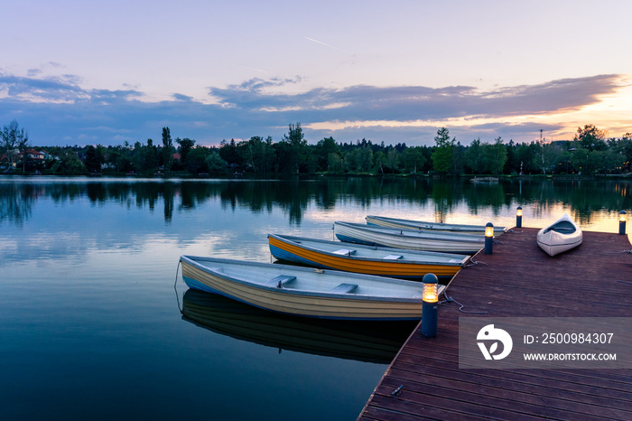 wooden boats on a calm lake called Csonakazo Lake in Szombathely Hungary at dusk after sunset