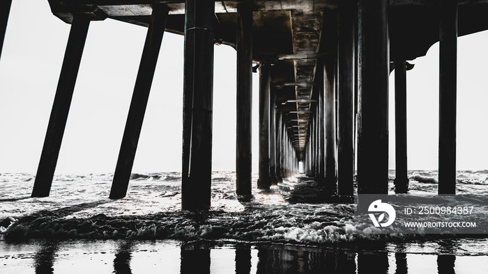 Monochromatic pier underside, abstract geometry of Huntington Beach Pier at low tide in California