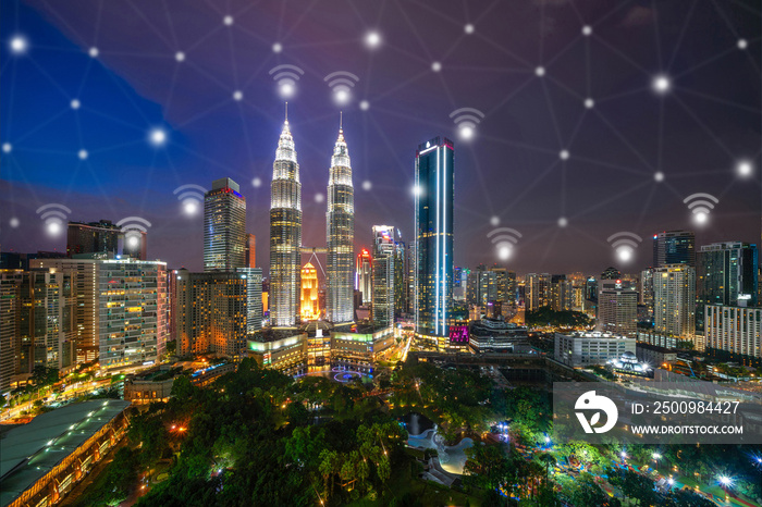 Digital network connection lines and wifi icons with Kuala Lumpur Downtown, Malaysia. Financial district in smart city in technology concept. Skyscraper and high-rise buildings at night