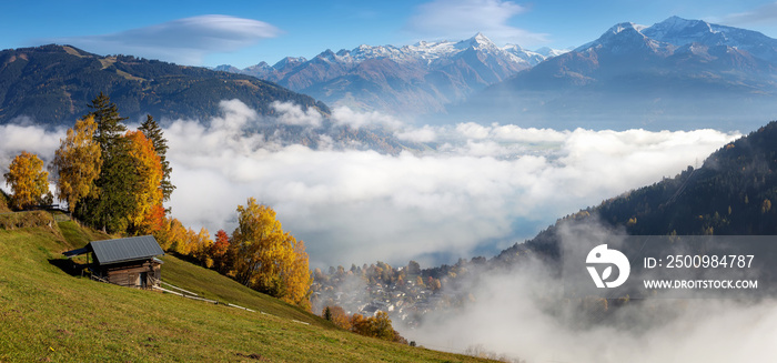 Colorful foggy morning in the Alps mountains. autumn foggy scenery. Amazing nature background. Mountainous autumn landscape. Red folliage on trees and fog in the distant valley. Zell am see lake