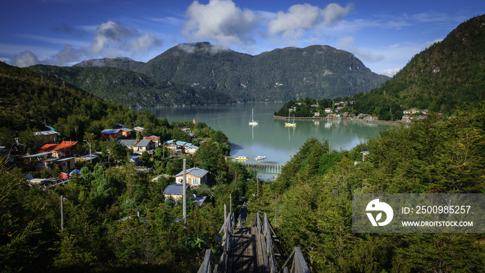 Beautiful panoramic view of the city of Caleta Tortel in Patagonia Chile. There are several houses between the forest, the Pacific Ocean between the fjords and several sailboats.