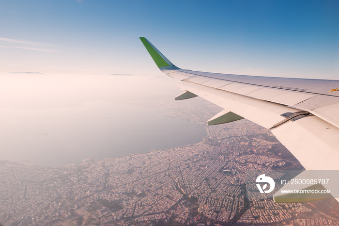 View from the window of the plane on the wing over the beautiful city of Thessaloniki in a haze of clouds