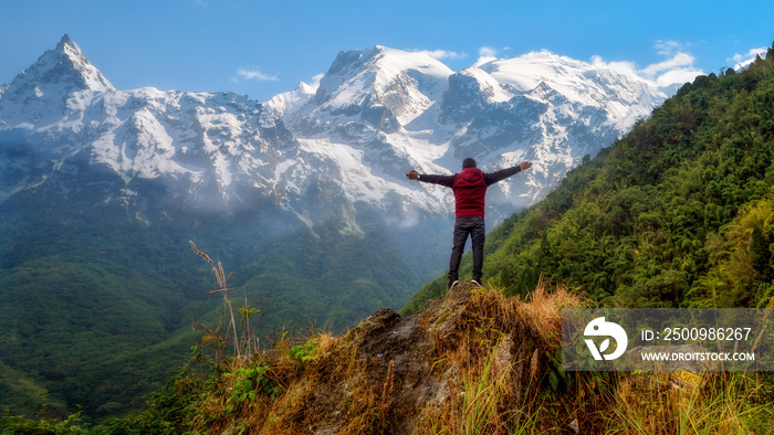 Male tourist stand on a hill top with arms spread overlooking the Himalayan mountain range at North Sikkim India.