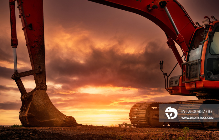 Backhoe parked at construction site after digging soil. Bulldozer on sunset sky and clouds background. Digger after work. Earth moving machine at construction site at dusk. Digger with old bucket.