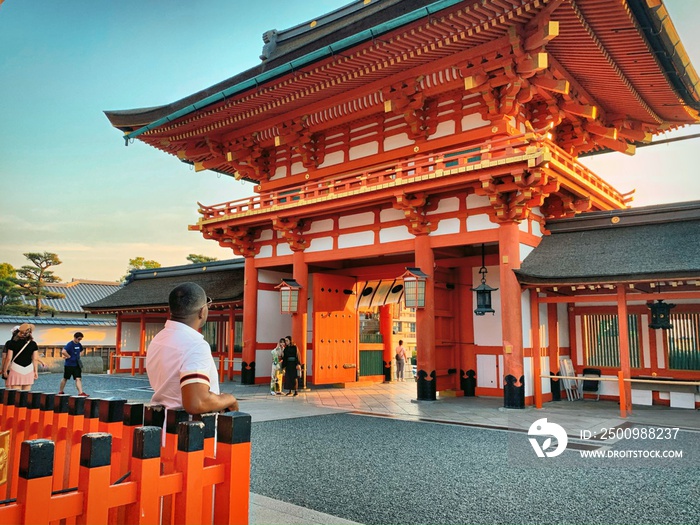 Black Man Admiring a Red Shrine & Temple in Kyoto, Japan at Sunset (Tourism in Far East Asia)