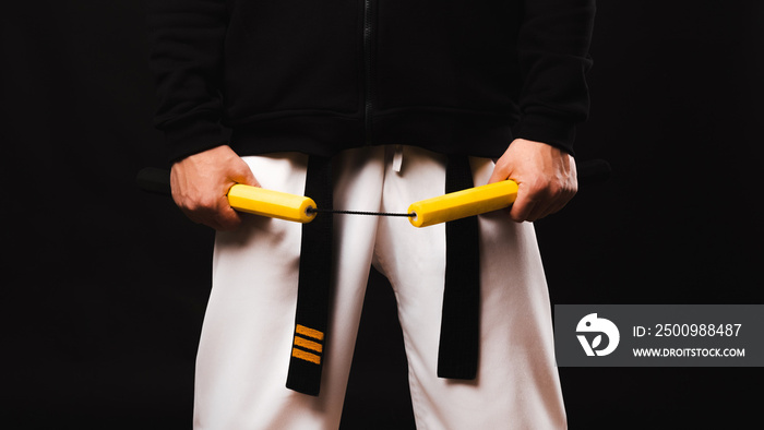 Close up photo of man in kimano holding nunchaku