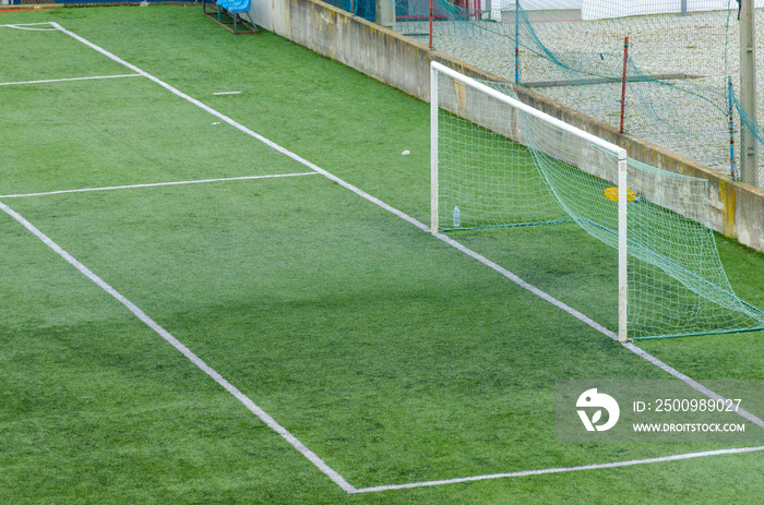 Detalle de la porteria y del area de un campo de futbol de hierba artificial.