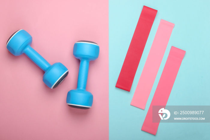 Dumbbells with fitness elastic bands on pink blue pastel background. Top view, flat lay